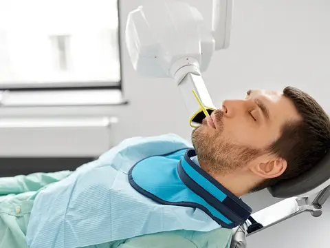 A patient in a protective apron having a digital X-ray taken in the dental chair