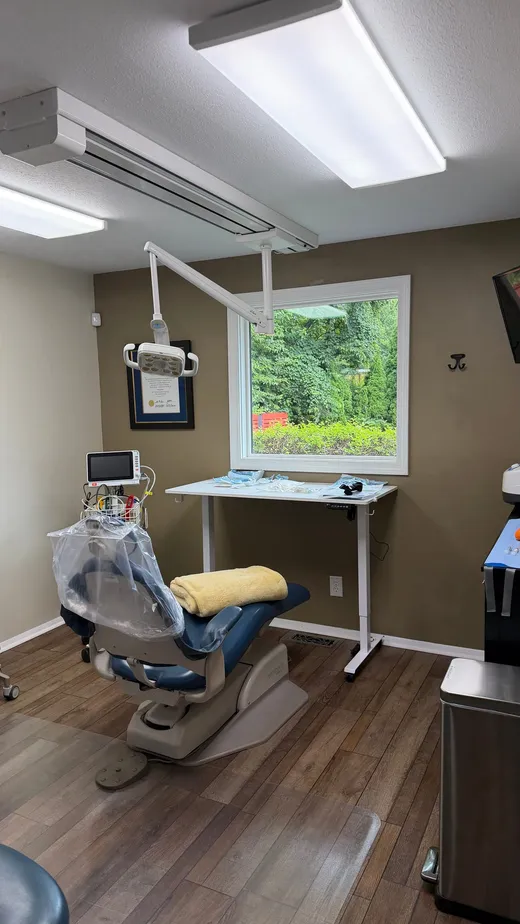 Treatment room with patient chair, monitoring cart, and adjustable-height work table
